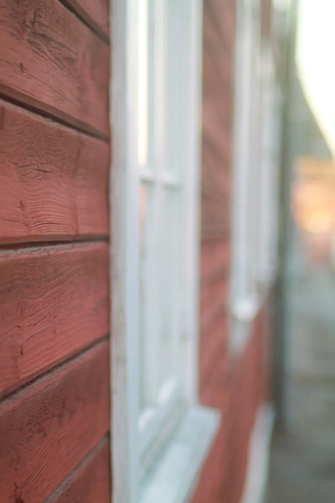 En liten grupp samlas vid faluröda trähus i skymningen