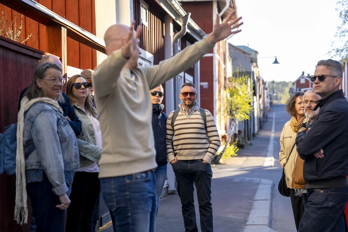 En liten grupp samlas vid faluröda trähus i skymningen