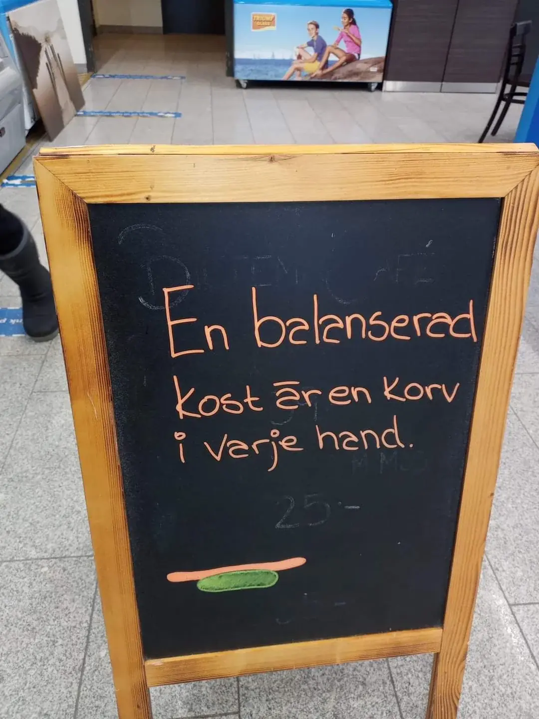 A chalkboard sign outside a café reading: En balanserad kost är en korv i varje hand
