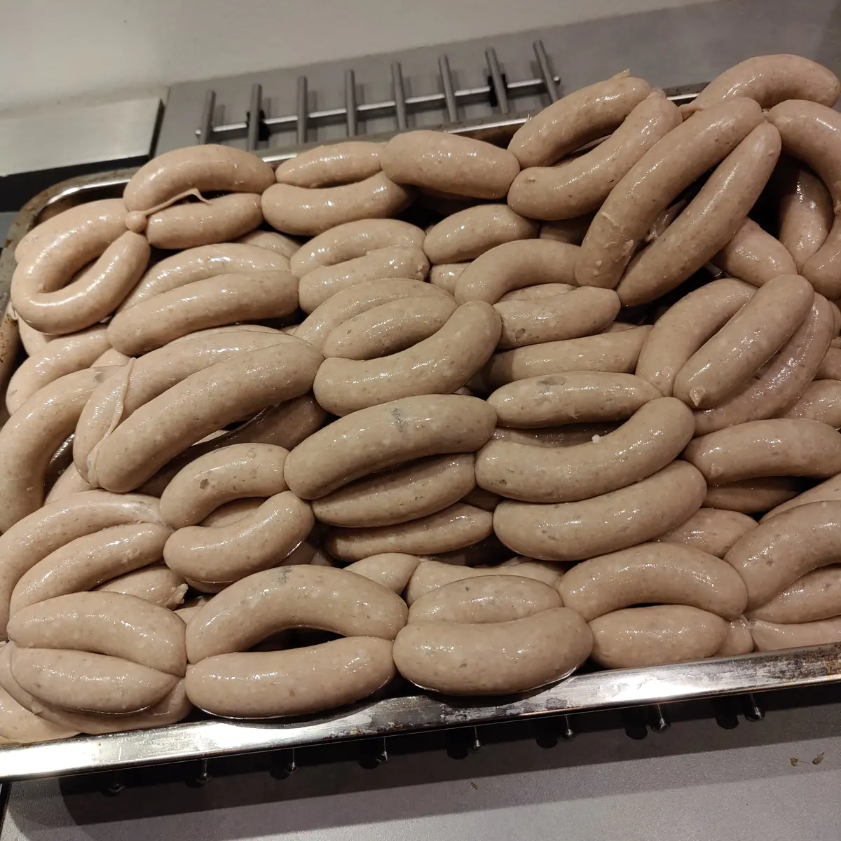 A large tray filled with freshly stuffed pale sausages